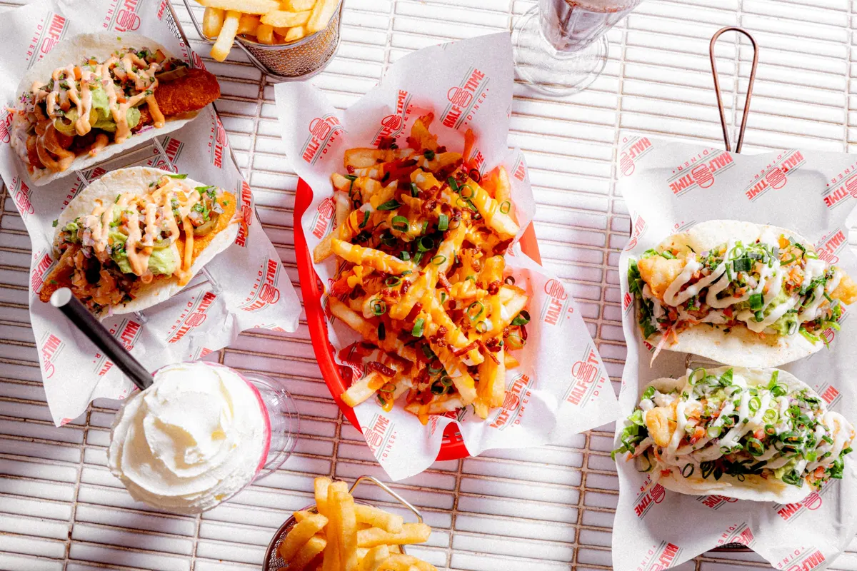 Overhead diner spread of tacos, loaded fries and sides