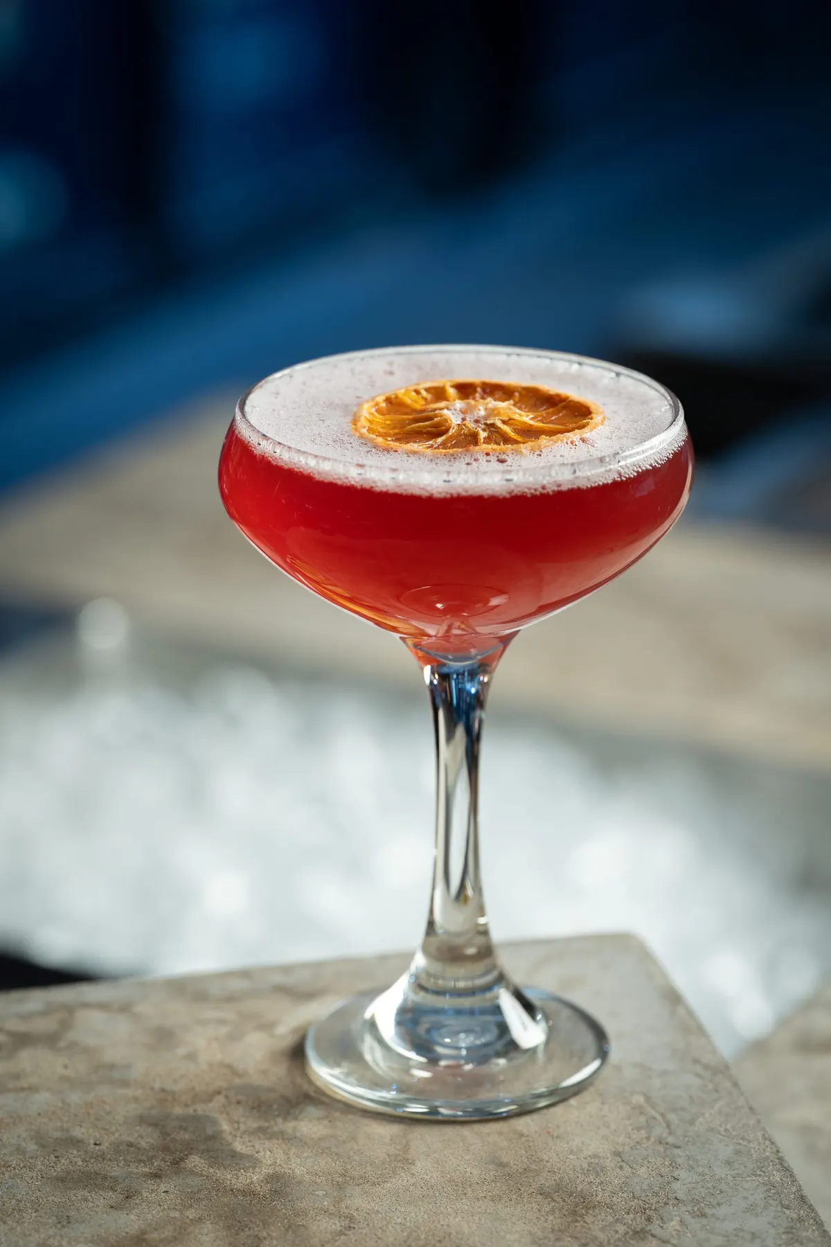 Pink sour cocktail garnished with dried citrus