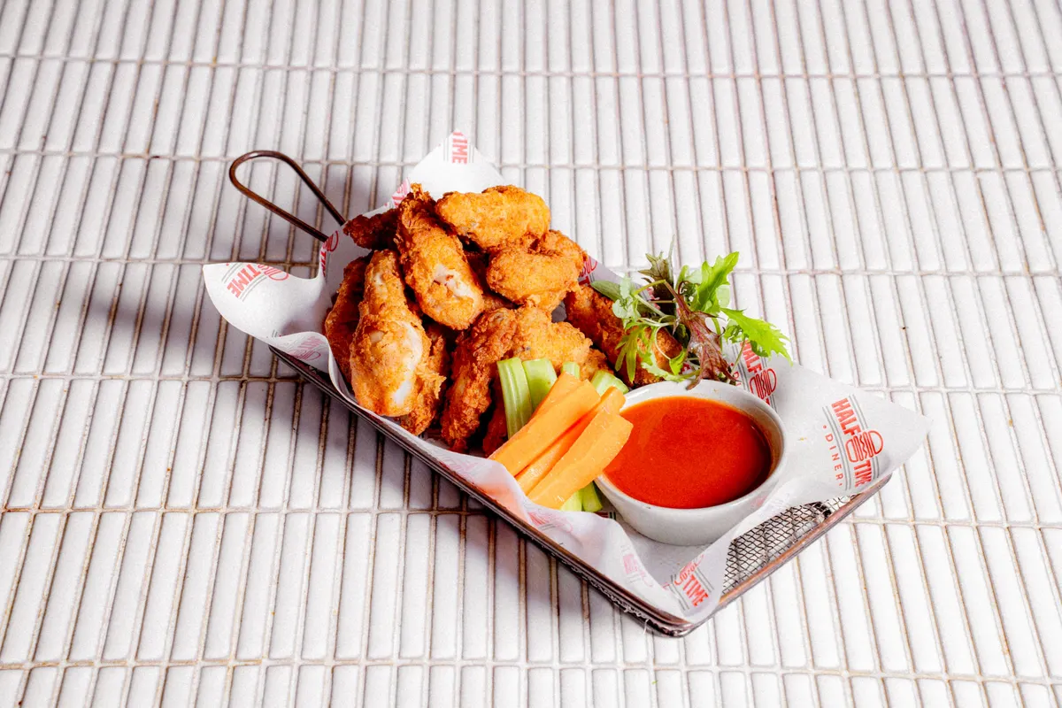 Crispy chicken wings with celery, carrot and hot sauce