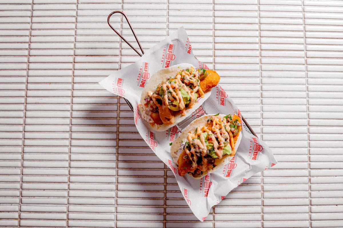 Two loaded tacos on diner paper, from above