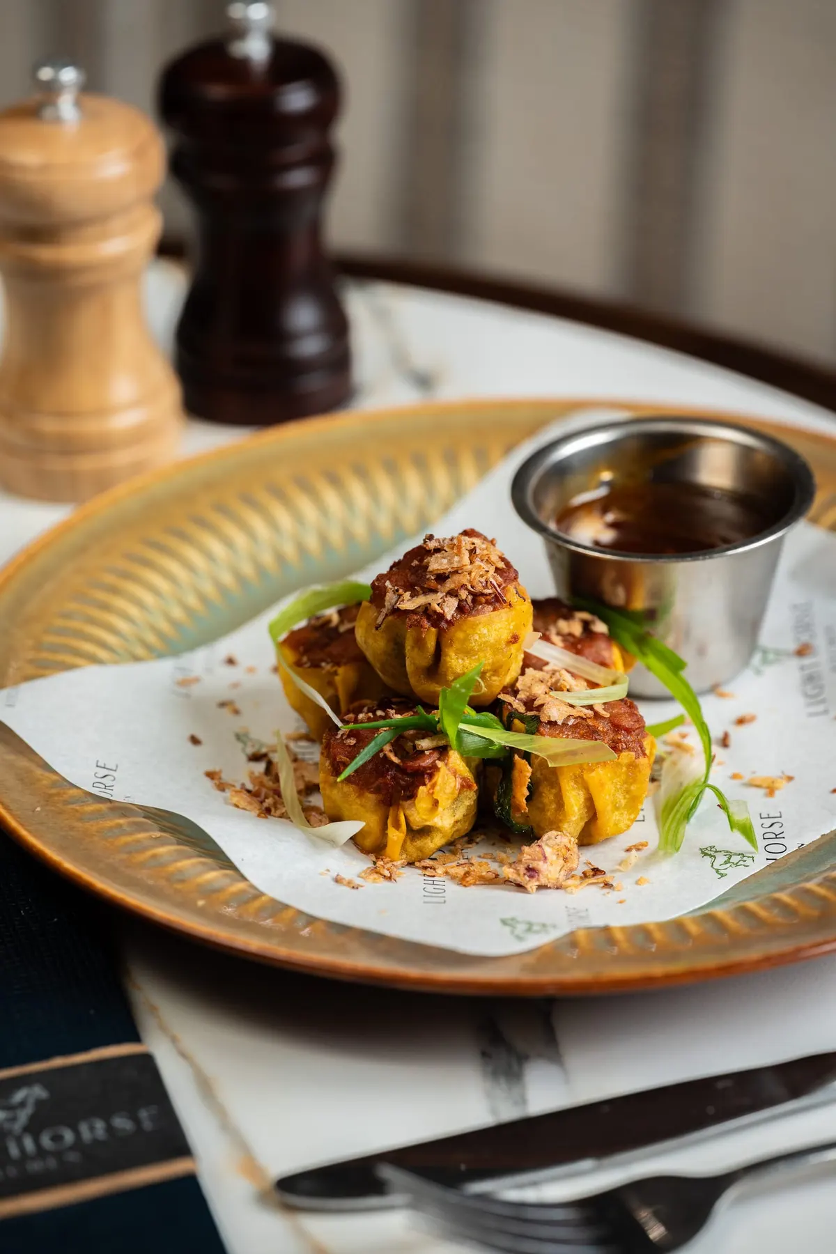 Dumplings topped with fried shallots and spring onion, with dipping sauce