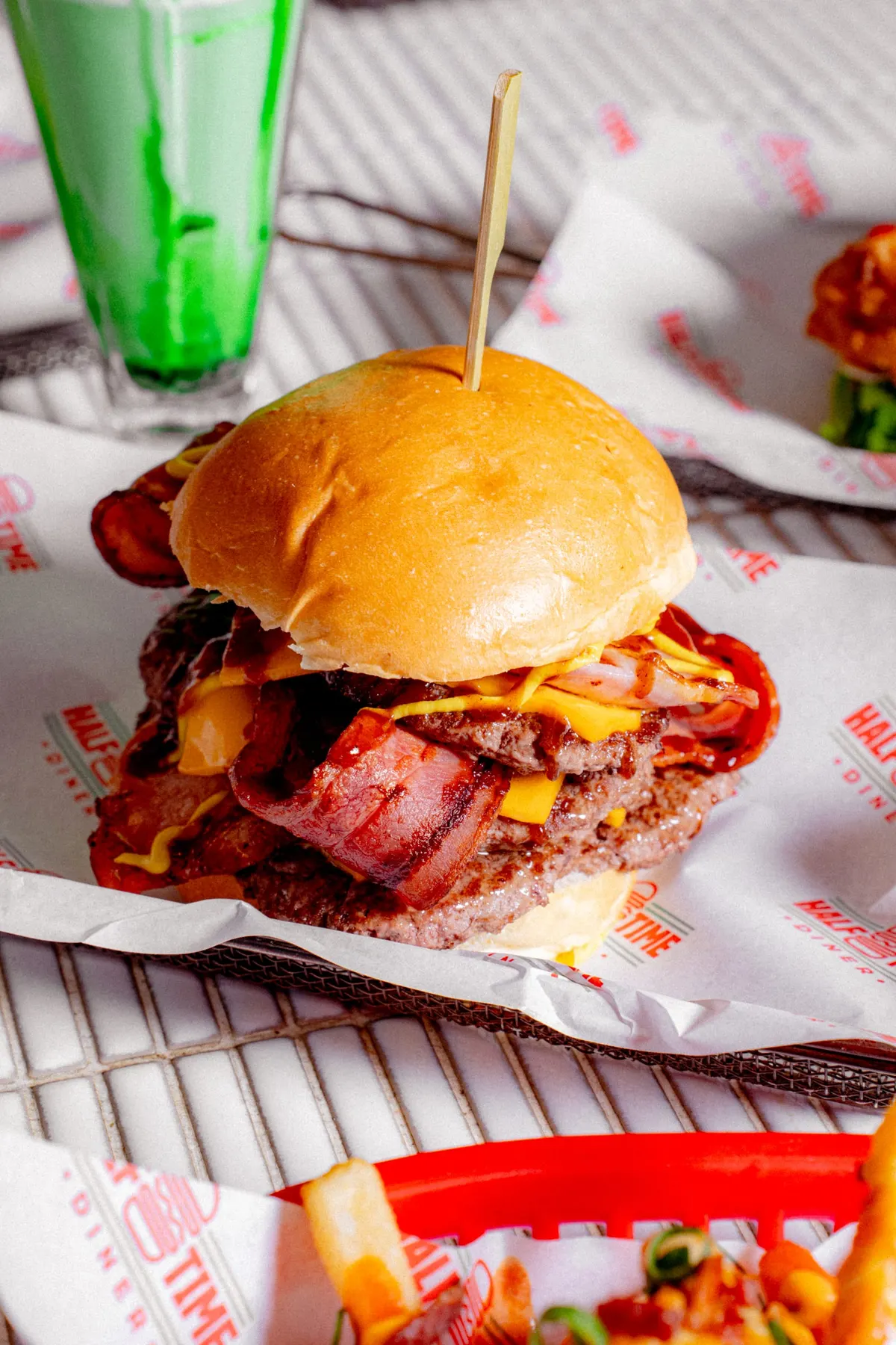 Bacon cheeseburger beside a green soda spider